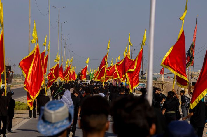 Pilgrims carrying red and black flags march toward Karbala, part of this year's Karbala Arbaeen preparations.